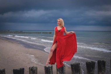 İlginç bir tatil sahili konsepti. Deniz kıyısında kırmızı elbiseli güzel bir kadın..