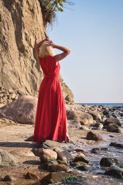 Yaratıcı tatil deniz kenarı seansı. Sahilde zarif kırmızı elbisesiyle güzel bir kadın..