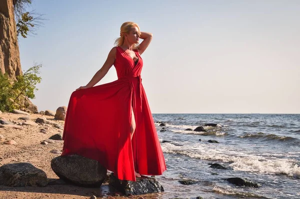 Yaratıcı tatil deniz kenarı seansı. Sahilde zarif kırmızı elbisesiyle güzel bir kadın. Kendi konseptiniz veya metniniz için alanı olan çerçeve.