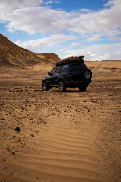 SUV, araba, Sahra 'daki dağların yakınındaki çölde safari..
