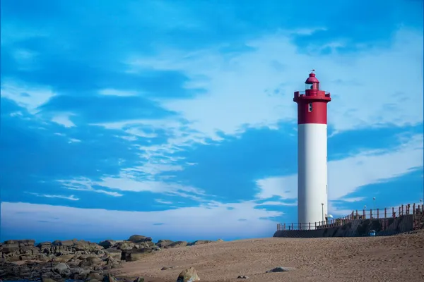 Kıyı deniz manzarası, ünlü kırmızı ve beyaz deniz fenerine ve mavi gökyüzüne karşı, Durban, Güney Afrika yakınlarında Umhlanga..