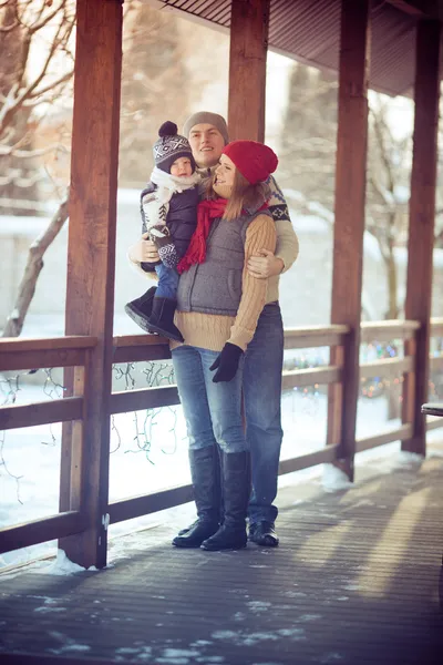 Glad ung familj porträtt på vintern omgiven av snö. — Stockfoto