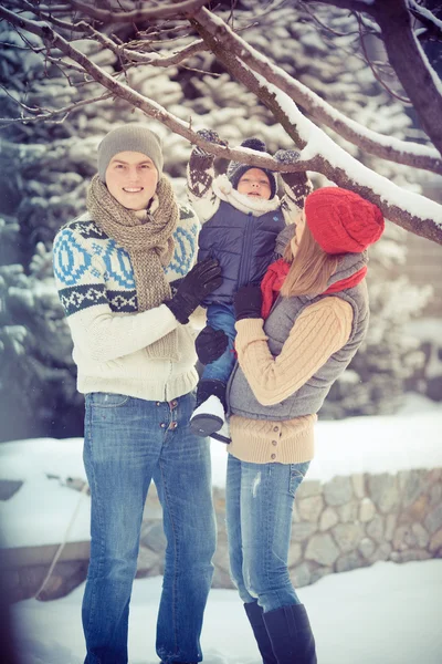 Happy young family portrait on winter surrounded by snow. — Stock Photo, Image