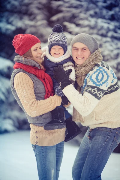 Happy young family portrait on winter surrounded by snow. — Stock Photo, Image