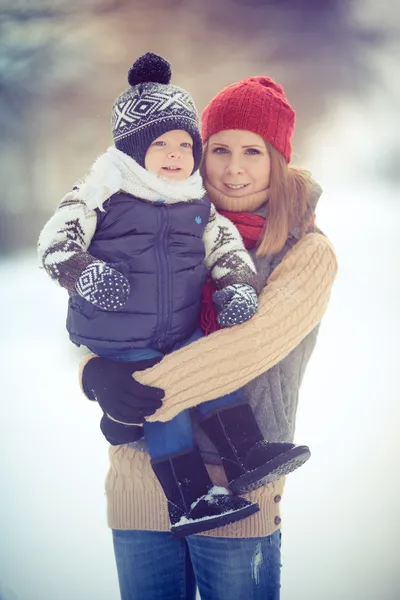 Glad ung familj porträtt på vintern omgiven av snö. Royaltyfria Stockbilder