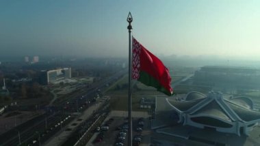 Beyaz Rusya bayrağı mavi gökyüzü ve güneşli bir sabahta Minsk şehri üzerinde dalgalanıyor.