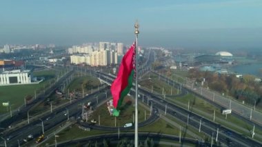 Beyaz Rusya bayrağı mavi gökyüzü ve güneşli bir sabahta Minsk şehri üzerinde dalgalanıyor.