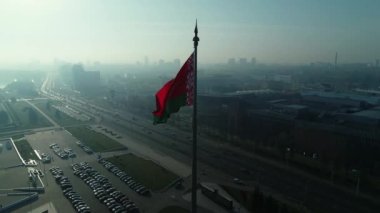 Beyaz Rusya bayrağı mavi gökyüzü ve güneşli bir sabahta Minsk şehri üzerinde dalgalanıyor.