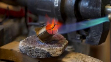 Craftsman soldering the metal tip of the scabbard in the workshop