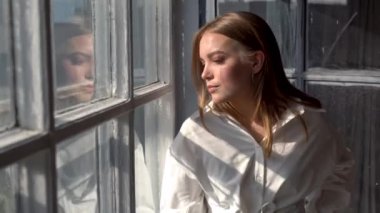 Güneşli bir günde pencerenin yanında poz veren rahat bir model.