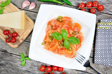 Parmesanlı ve fesleğenli bir tabakta kırmızı kalp ravioli.