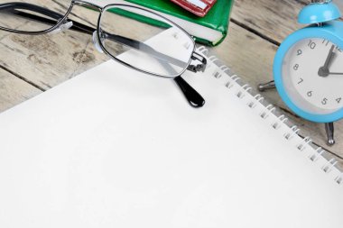 Çalar saat, kalem ve defter ahşap masada.