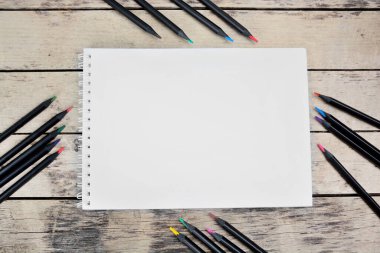 Masasında siyah renkli kalemler olan boş bir defter