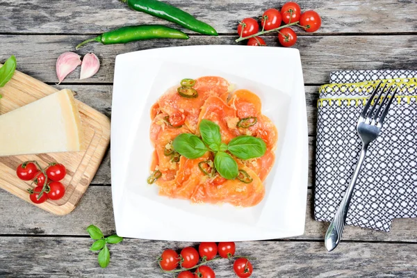 Masada parmesan ve fesleğenli bir tabakta kırmızı kalp ravioli.