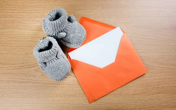 Botas Bebê Cinza Com Papel Vazio Envelope Laranja Mesa — Fotografia de Stock