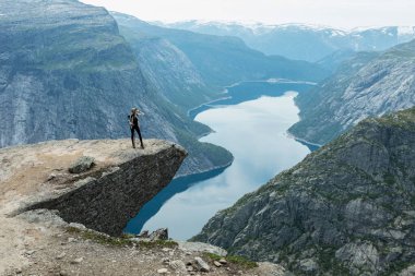 Genç bir kadın Norveç 'in Vestland ilçesindeki Trolltunga uçurumunda poz veriyor.