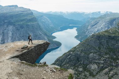 Genç bir kadın Norveç 'in Vestland ilçesindeki Trolltunga uçurumunda yürüyor.