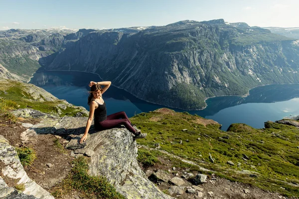 Egy fiatal és gyönyörű nő pózol a sziklán, aki a Ringedalsvatnet-tavat figyeli Oddában, Vestland megyében, Norvégiában. — Stock Fotó