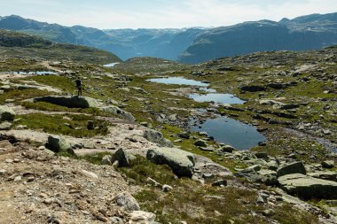 Norveç 'in Vestland ilçesi Trolltunga' ya giden yürüyüş yolunda bir kadın kayanın üzerinde duruyor.