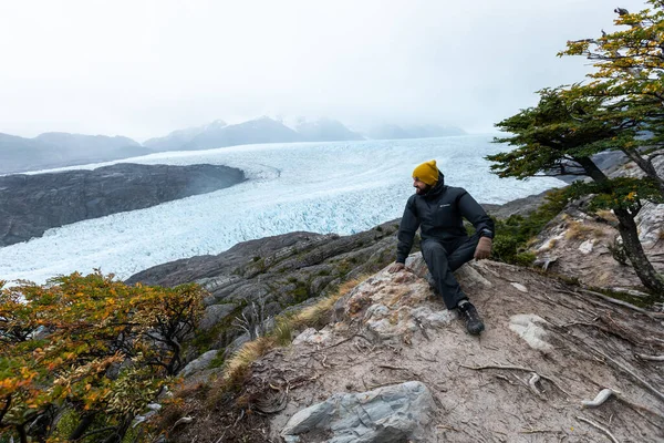 Un jeune homme est assis sur le rocher avec le glacier Grey en arrière-plan, Parc national Torres del Paine, Chili — Photo