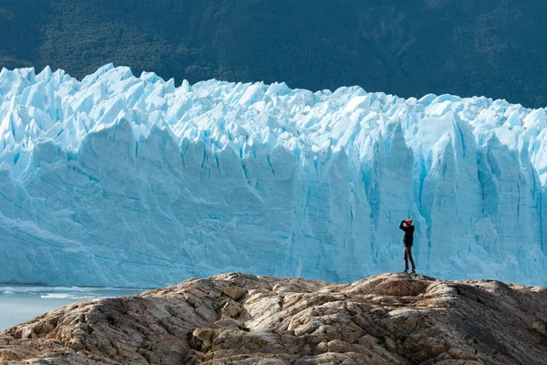 Egy nő áll a sziklán, és a Perito Moreno gleccsert nézi. — Stock Fotó