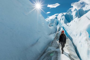 Bir kadın Perito Moreno Buzulu 'nun buz oluşumunda yürür ve sola bakar.