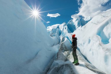 Bir kadın Perito Moreno Buzulu 'nda karlı duvarların arasında duruyor ve arkasına bakıyor.