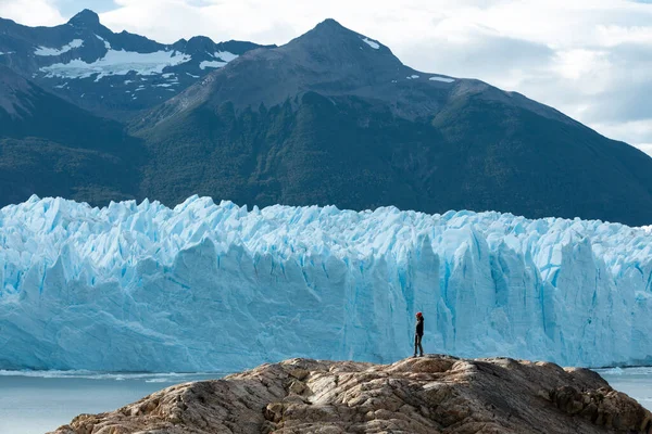 Bir kadın kaya oluşumunda duruyor ve Perito Moreno Buzulu 'na bakıyor.