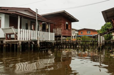 Sudaki evler ve su yüzeyindeki çöp yüzeyi, Bangkok, Tayland
