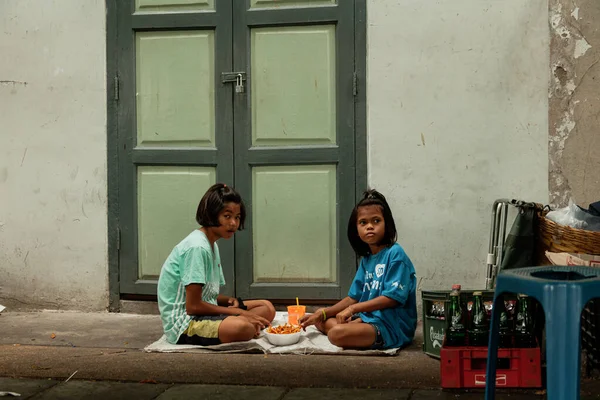 BANGKOK, THAILAND - 3 Mayıs 2014: İki küçük kız yerde atıştırmalıklarını yiyorlar — Stok fotoğraf