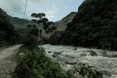 CUSCO, PERU - 9 Mart 2019: Turistler hızlı akan Urubamba deresi boyunca yaya yolunda yürürler