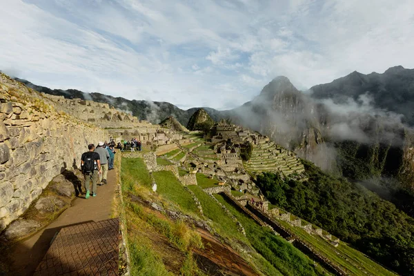 MACHU PICCHU, PÉROU - 9 MARS 2019 : Un groupe de touristes marche sur les ruines du Machu Pichu — Photo