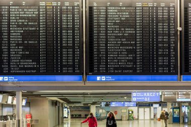 FRANKFURT, GERMANY - NOVEMBER 11, 2021: Two women in medical face masks walk with suitcases at the Frankfurt International airport