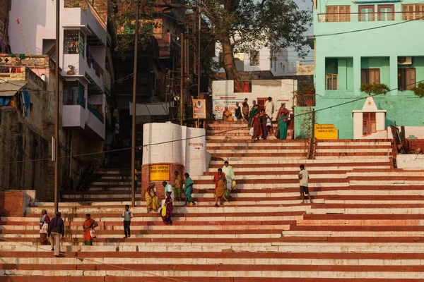 VARANASI, INDIA - NOVEMBER 12, 2014: Pilgrims go down the steps into the Ganges to perform their morning prayers along the Ganges River — Stok fotoğraf