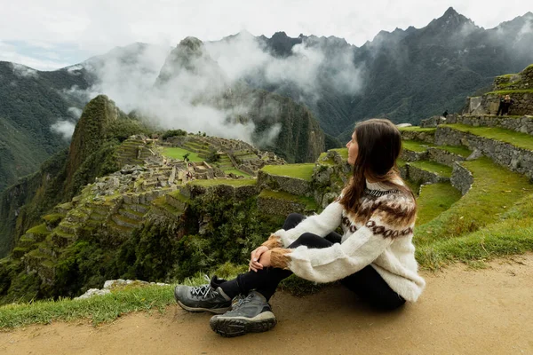 A young woman sitting on the ground at Machu Picchu, Peru — Stockfoto