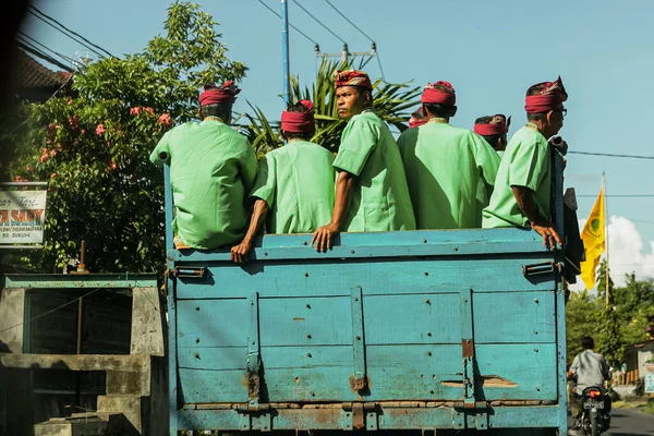 BALI, INDONESIA - MARCH 1, 2014: Local Balinese men in green batic shirts sit on the truck — Stock Photo, Image
