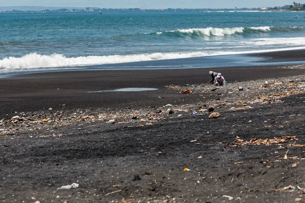BALI, INDONESIA - 1 ΜΑΡΤΙΟΥ 2014: Οι άνθρωποι συλλέγουν κάτι από τα σκουπίδια που ρίχνονται στην παραλία δίπλα στον ωκεανό — Φωτογραφία Αρχείου