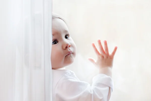 Cute little girl sits at window portrait — Stock Photo, Image