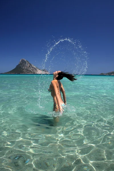 Krásná mladá žena, stříkající vodě s vlasy. — Stock fotografie