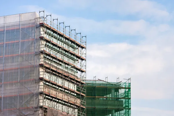 Trappa och byggnadsställningar på en byggarbetsplats, täckt med mesh på himmel bakgrund. — Stockfoto