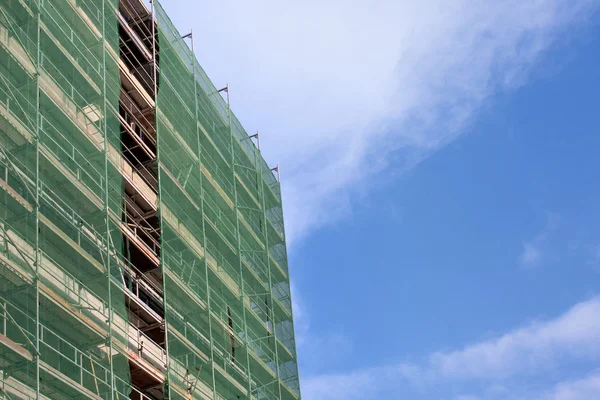 Treppe und Baugerüst auf einer Baustelle, mit Netz auf Himmelshintergrund abgedeckt. — Stockfoto