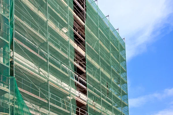 Treppe und Baugerüst auf einer Baustelle, mit Netz auf Himmelshintergrund abgedeckt. — Stockfoto