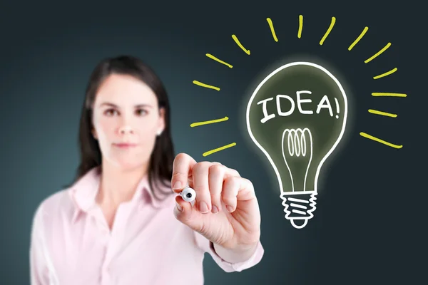 Young business woman drawing a light bulb. — Stock Photo, Image