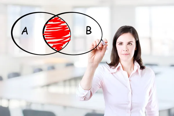 Young businesswoman drawing intersected circle diagram on whiteboard. Office background.