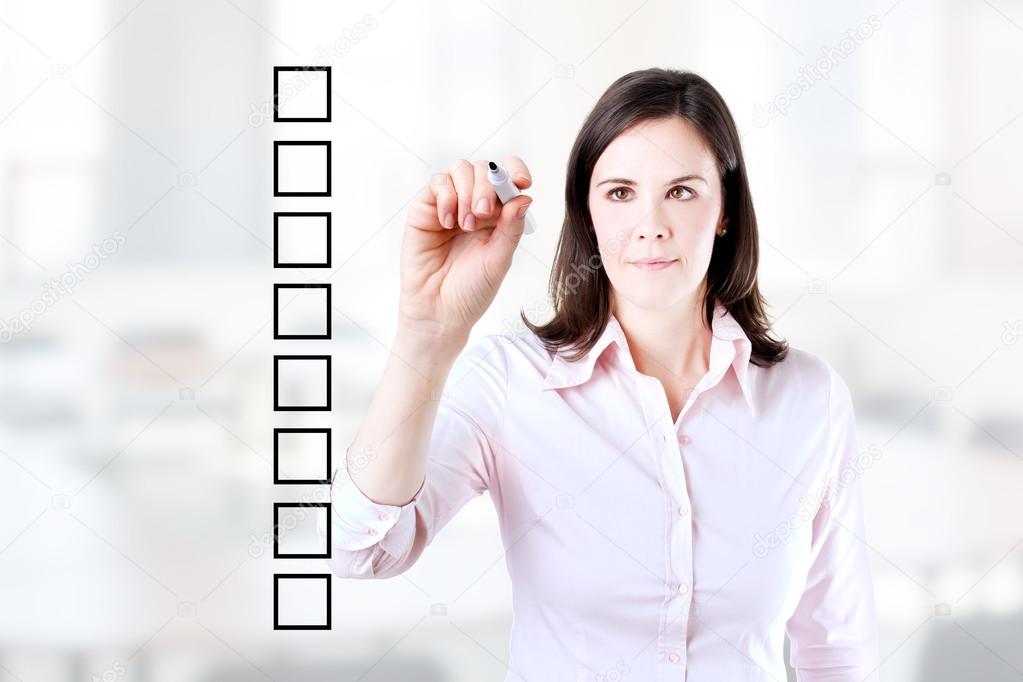 Business woman writing on some blank checklist boxes. Office background.