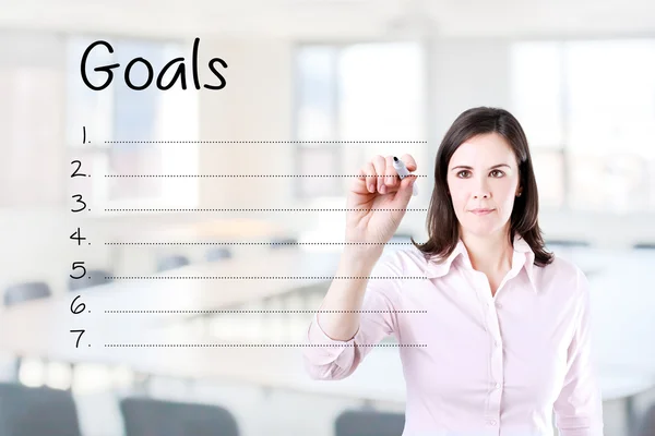 Business woman writing blank goal list. Office background. — Stock Photo, Image