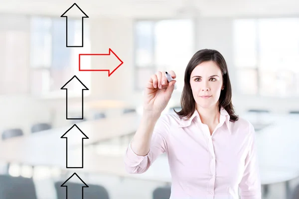 Businesswoman drawing arrows in different directions. Office background. — Stock Photo, Image