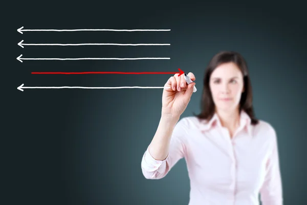 Businesswoman drawing arrows in different directions. Blue background. — Stock Photo, Image