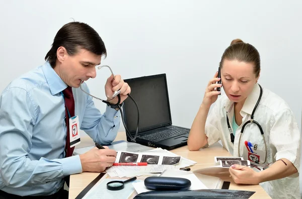 Man en vrouw artsen nemen raadsman achter een bureau — Stockfoto