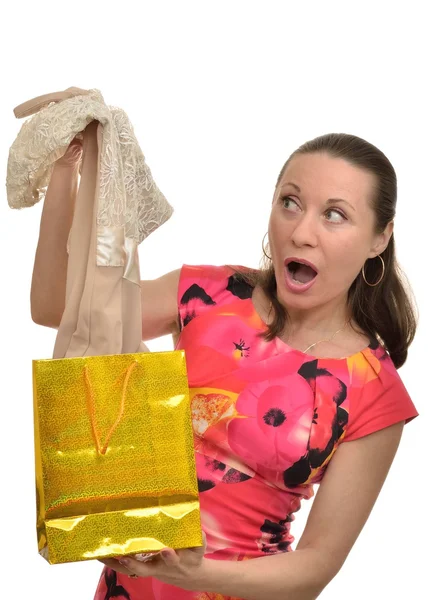 Woman with surprise examines new clothes obtained as a gift — Stock Photo, Image